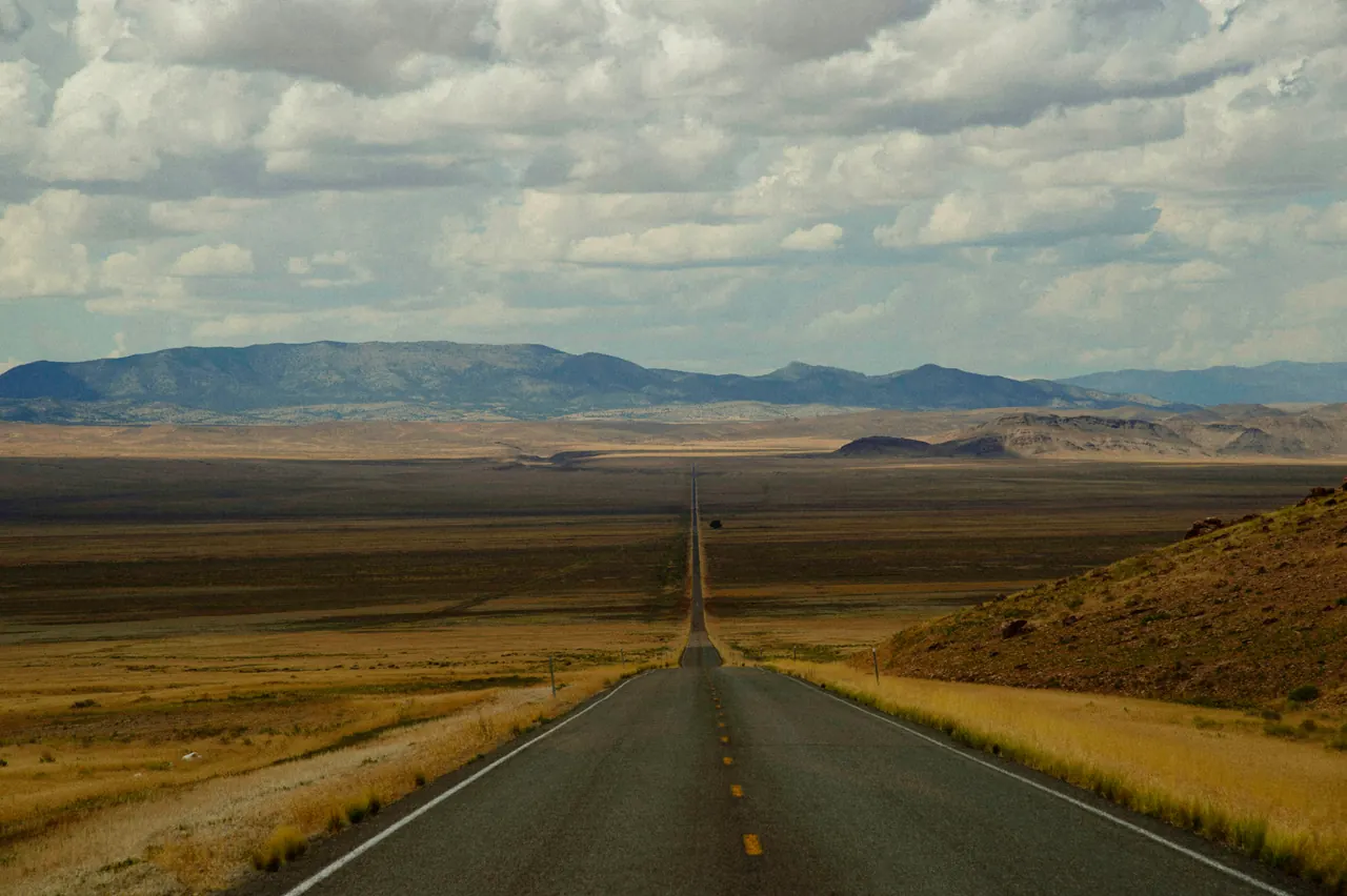 An open road crossing a wide Nevada valley toward distant mountains.
